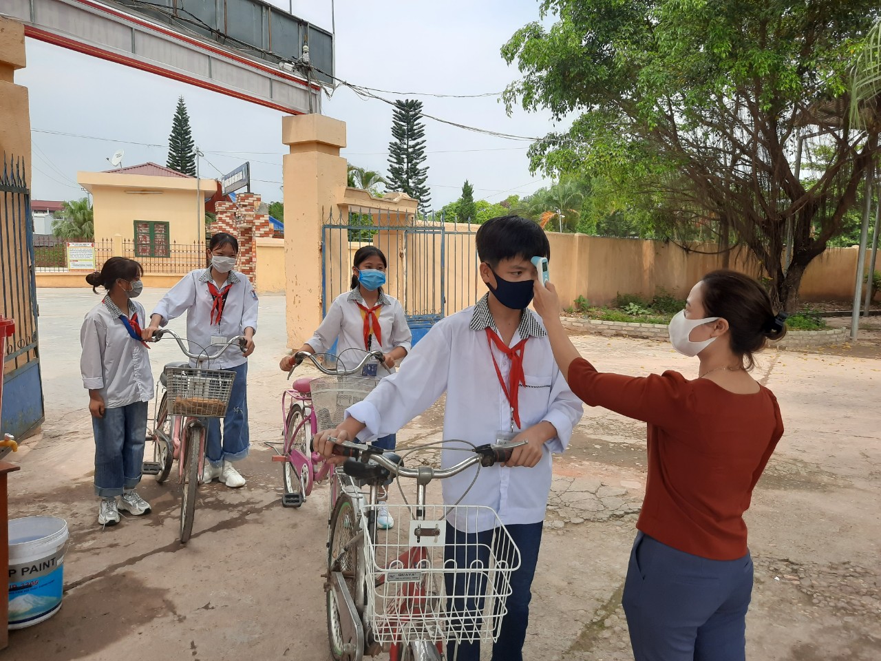 Nhân viên y tế đo thân nhiệt cho học sinh ngay tại cổng trường